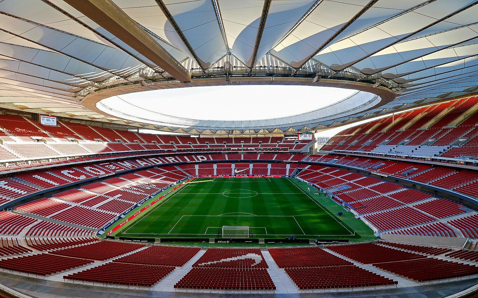 Cívitas Metropolitano Stadium interior with empty red seats and green soccer field.