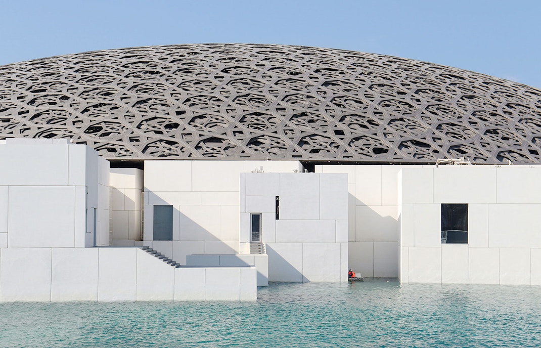 Louvre Abu Dhabi's dome and modern architecture over water.
