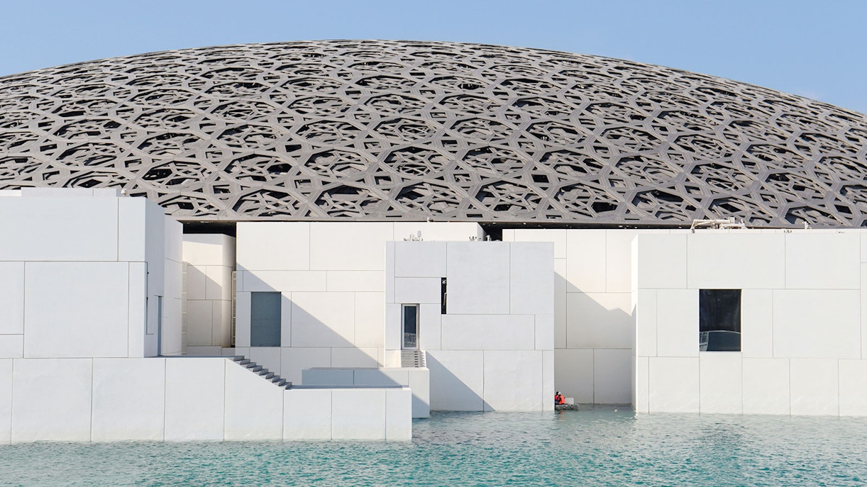 Louvre Abu Dhabi's dome and modern architecture over water.