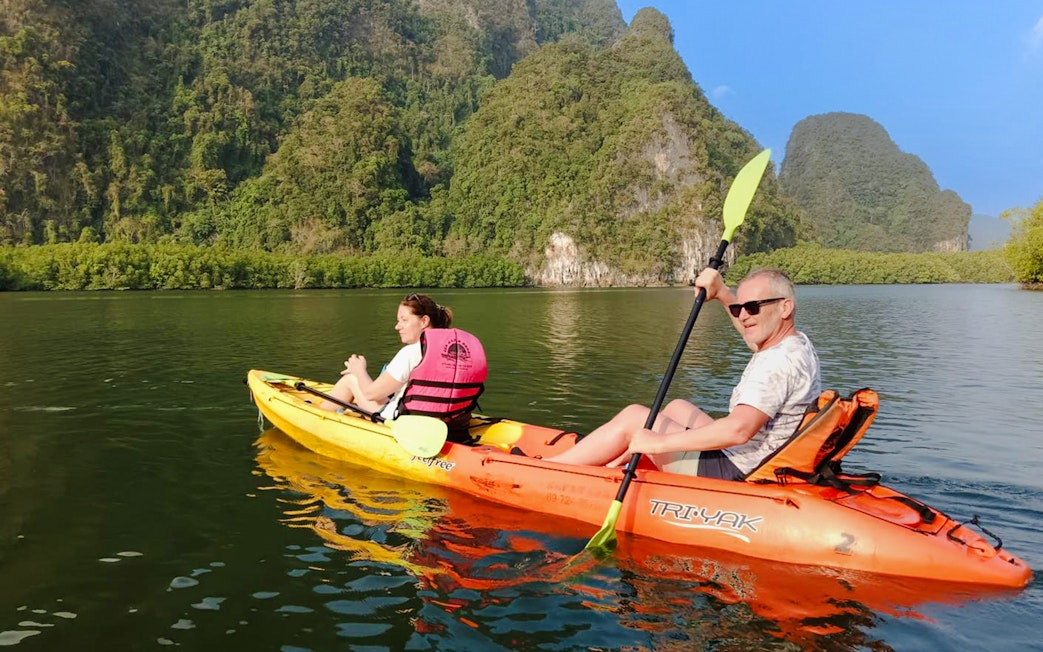 Tourists kayaking through Ao Thalane's scenic limestone cliffs and lush mangroves.