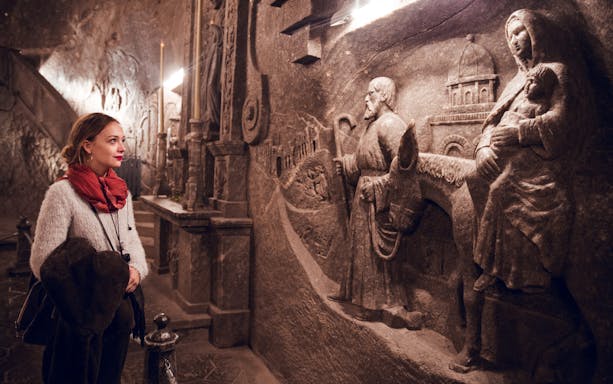 Visitor admiring intricate salt carvings in Wieliczka Salt Mine, Poland.
