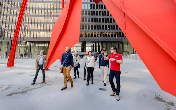 Guided group walking under Calder's Flamingo sculpture in Chicago.