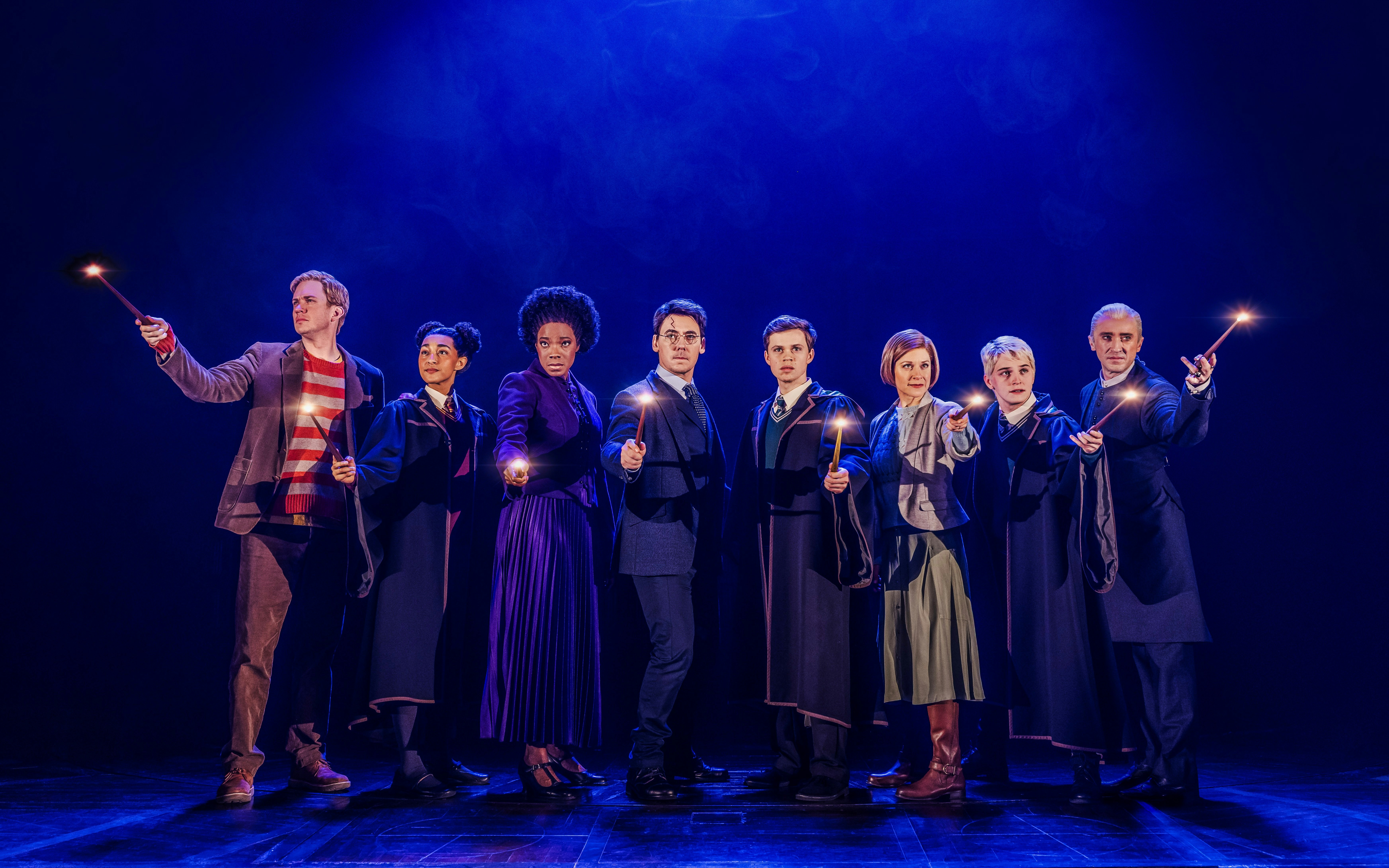 Cast of "Harry Potter and the Cursed Child" on Broadway holding wands on stage.