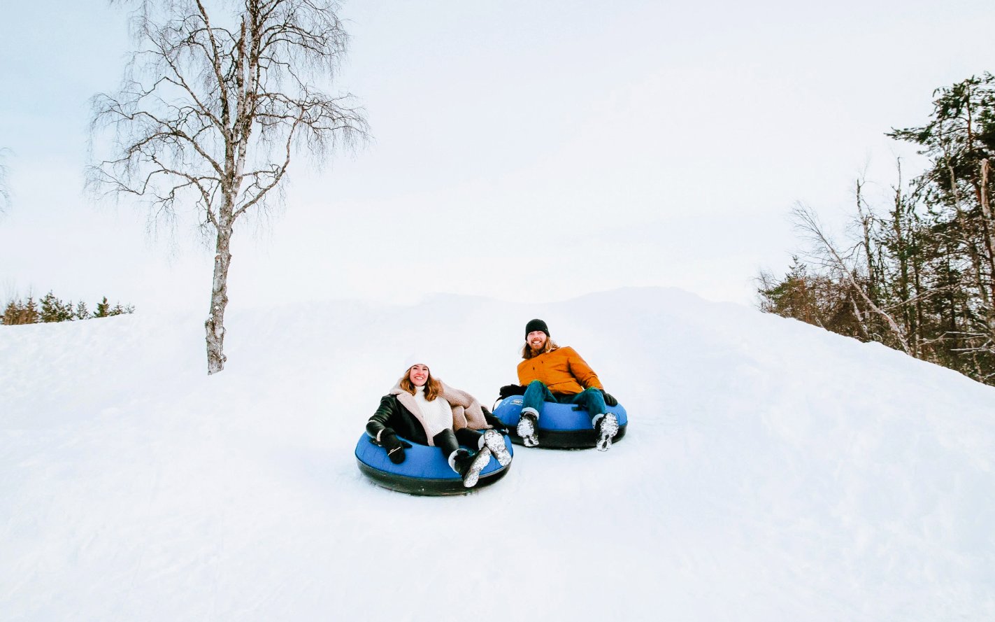 Guests sledding on snow tubes outside Arctic SnowHotel.