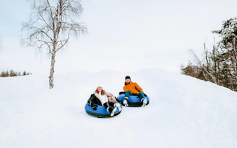 Guests sledding on snow tubes outside Arctic SnowHotel.