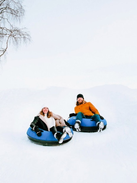 Guests sledding on snow tubes outside Arctic SnowHotel.