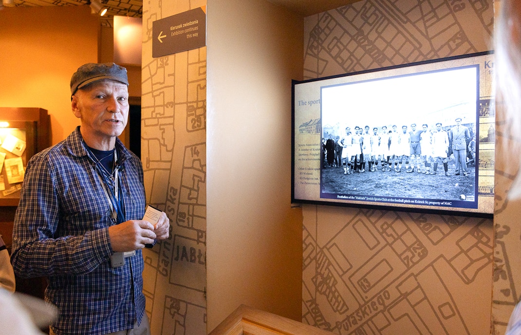 Guide explaining exhibit at Oskar Schindler's Factory in Krakow, featuring historical photo.