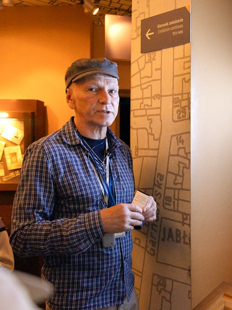 Guide explaining exhibit at Oskar Schindler's Factory in Krakow, featuring historical photo.