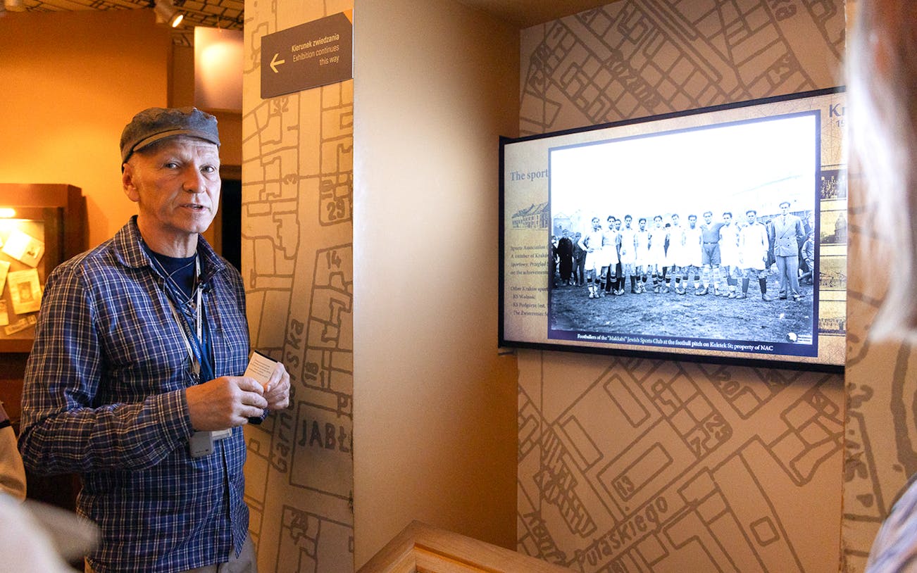 Guide explaining exhibit at Oskar Schindler's Factory in Krakow, featuring historical photo.