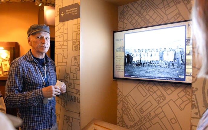 Guide explaining exhibit at Oskar Schindler's Factory in Krakow, featuring historical photo.