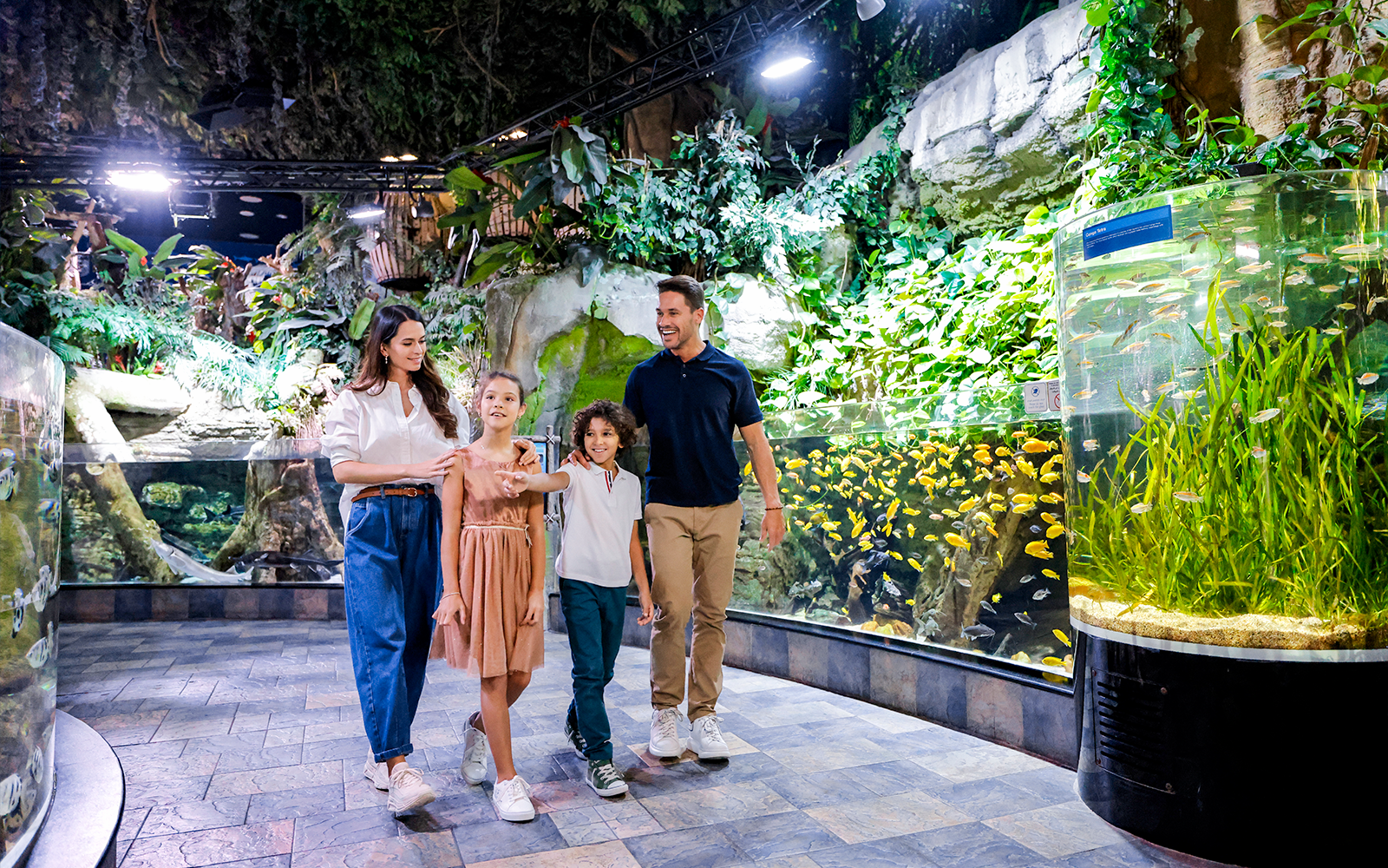 Family exploring vibrant fish tanks at Dubai Aquarium.