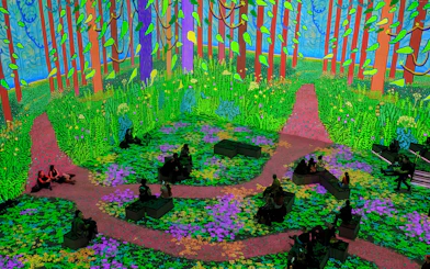 Immersive digital forest scene from David Hockney: Bigger & Closer exhibition with seated visitors.