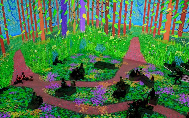 Immersive digital forest scene from David Hockney: Bigger & Closer exhibition with seated visitors.