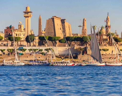 Sailboats on the Nile River with Luxor Temple in the background, Egypt.