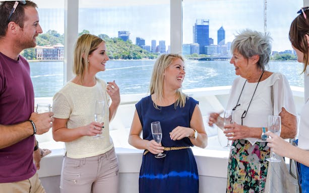 Group enjoying wine on a cruise with Perth skyline in the background.