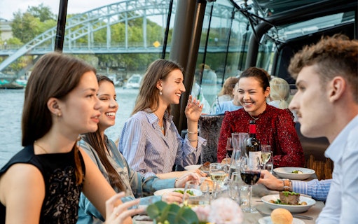 People dining on a Seine River lunch cruise with a view of a bridge in Paris.