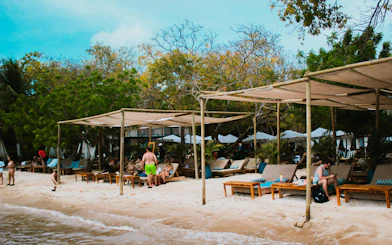 Shaded seating area at Islabela beach club, Rosario Islands, with white sand and lounge chairs.