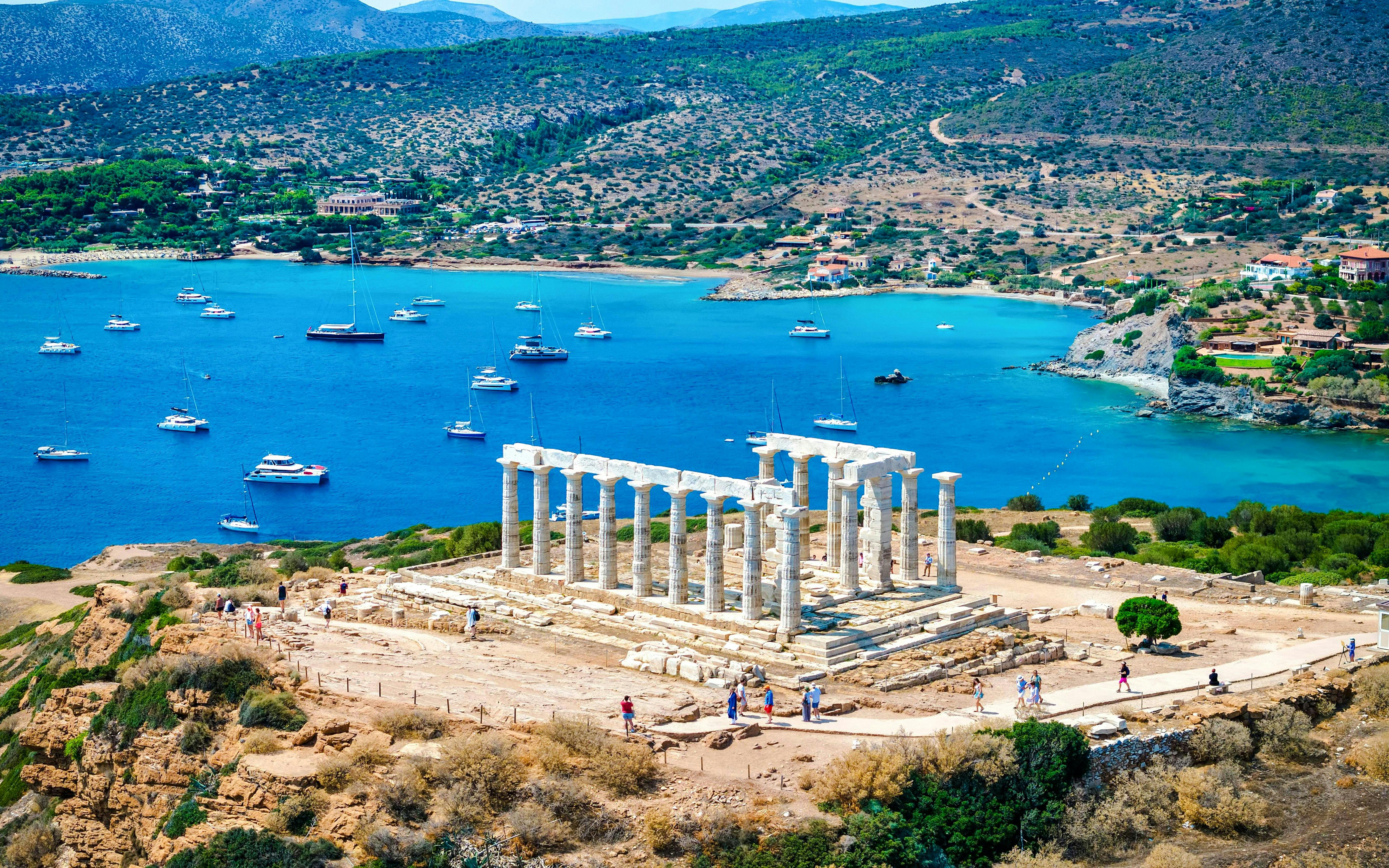 Cape Sounio with Poseidon Temple overlooking the Aegean Sea and anchored boats.