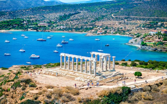 Cape Sounio with Poseidon Temple overlooking the Aegean Sea and anchored boats.