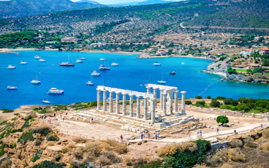 Cape Sounio with Poseidon Temple overlooking the Aegean Sea and anchored boats.
