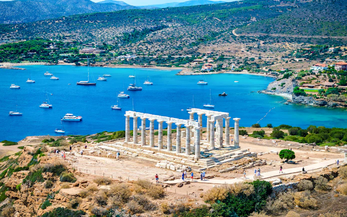 Cape Sounio with Poseidon Temple overlooking the Aegean Sea and anchored boats.