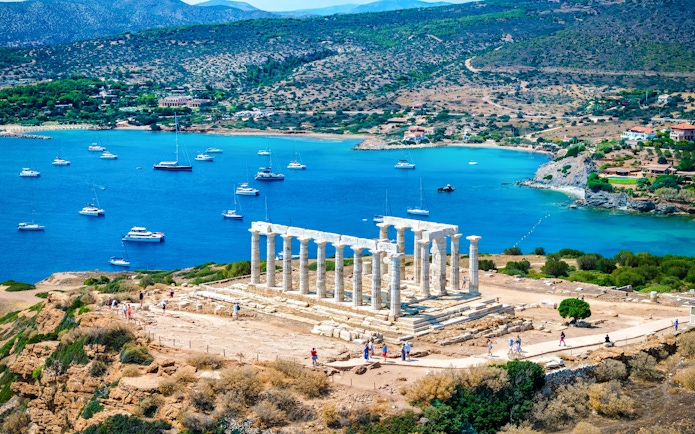Cape Sounio with Poseidon Temple overlooking the Aegean Sea and anchored boats.