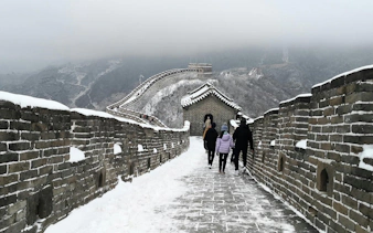 Visitors walking on snow-covered Mutianyu Great Wall, China.