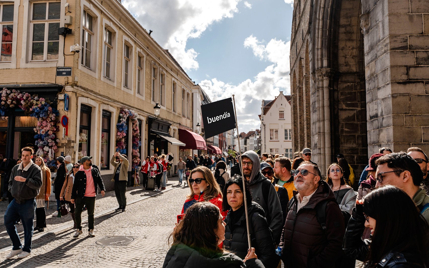 Tour group with guide holding sign in Bruges street.