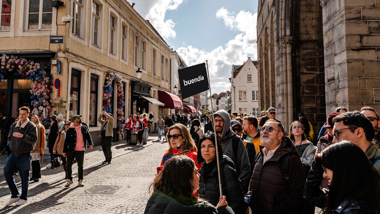 Tour group with guide holding sign in Bruges street.