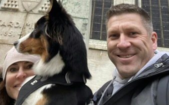 Couple with dog in front of a historic building in Brussels during city exploration game.