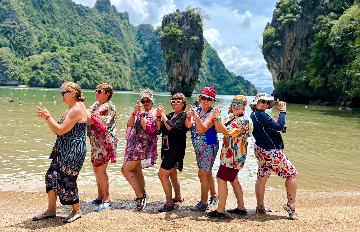 Tourists posing at James Bond Island, Phang Nga Bay, with limestone cliffs in the background, Phuket.