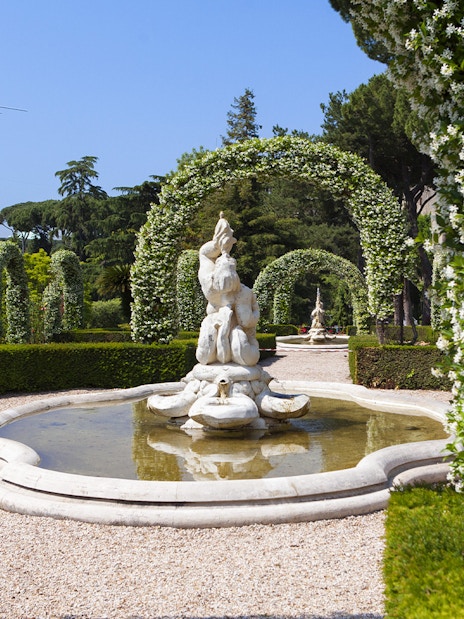 Vatican Gardens fountain surrounded by flowering arches on open bus tour.