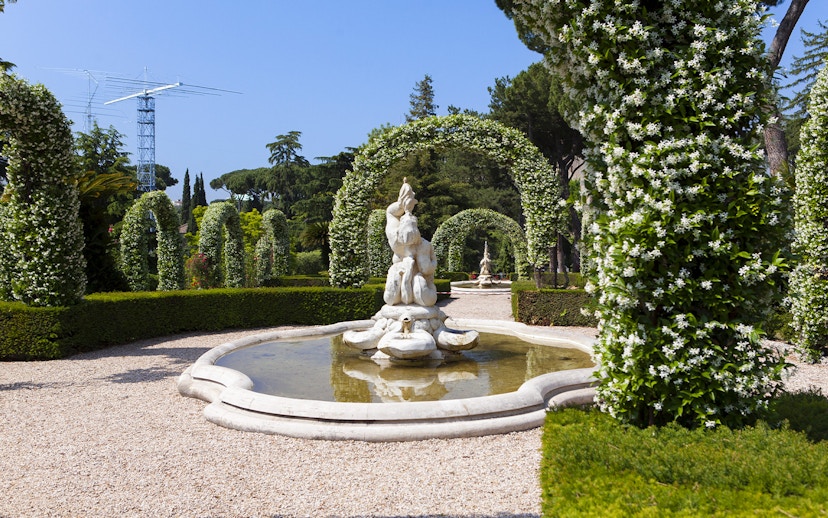 Vatican Gardens fountain surrounded by flowering arches on open bus tour.
