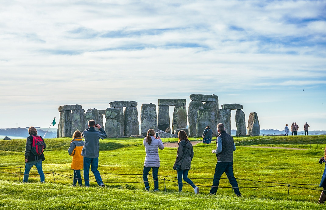 Tourists at Stonehenge, viewing ancient stone structures on a day trip from London.