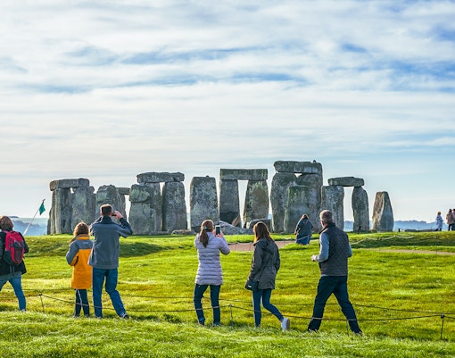 Tourists at Stonehenge, viewing ancient stone structures on a day trip from London.
