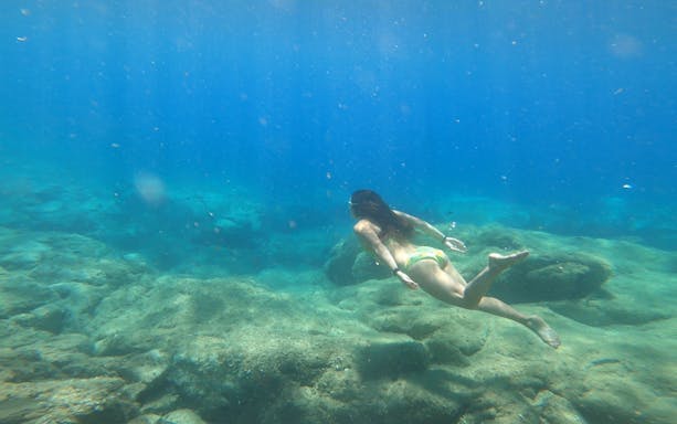 Young woman snorkeling over rocky seabed in Costa Brava.