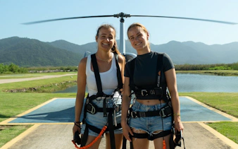 Tourists at helipad ready for Rio de Janeiro helicopter tour with mountains in background.