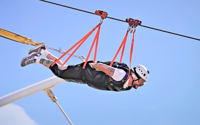 Person ziplining at Jais Adventure Park, UAE, wearing safety gear.