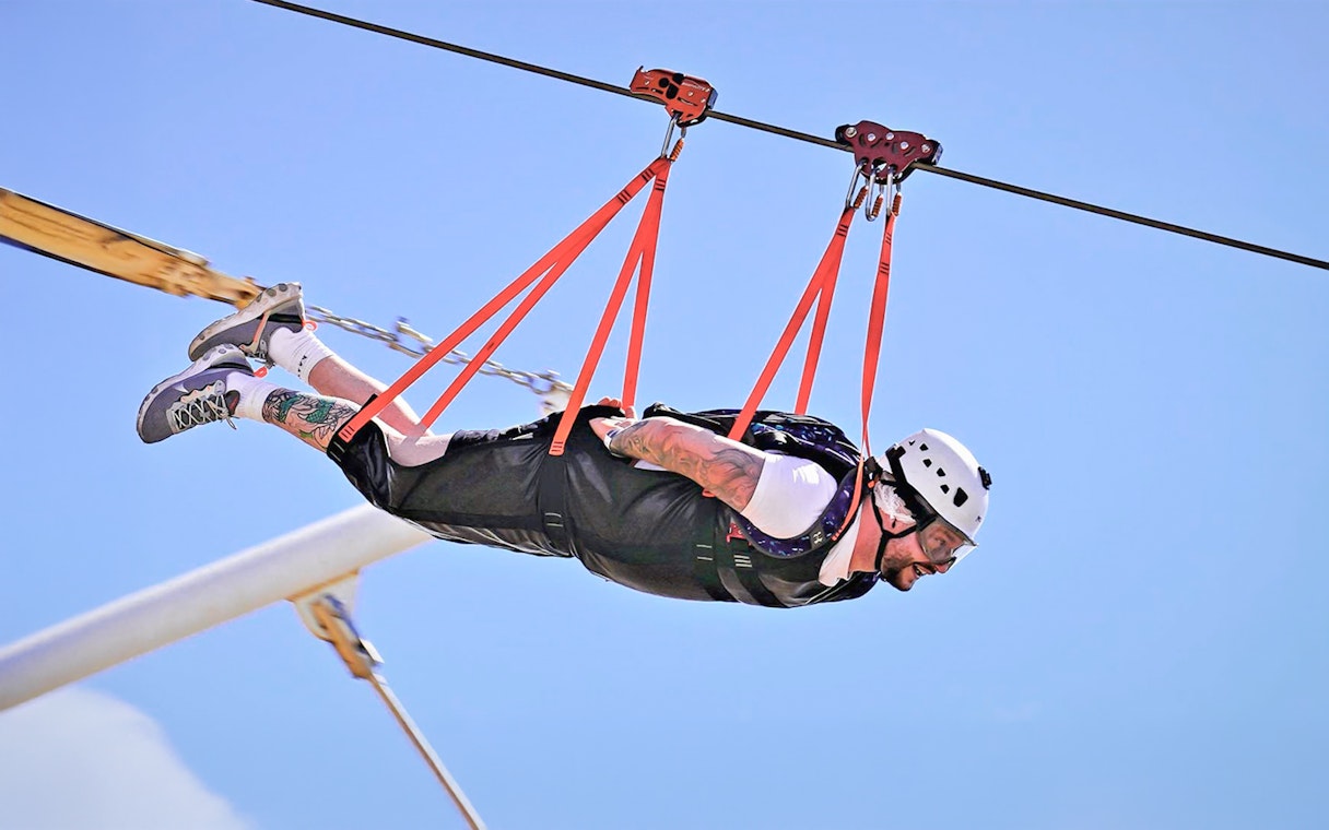 Person ziplining at Jais Adventure Park, UAE, wearing safety gear.