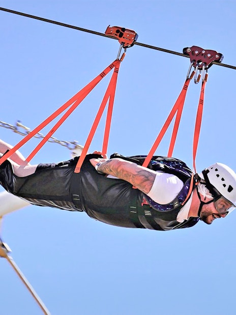 Person ziplining at Jais Adventure Park, UAE, wearing safety gear.