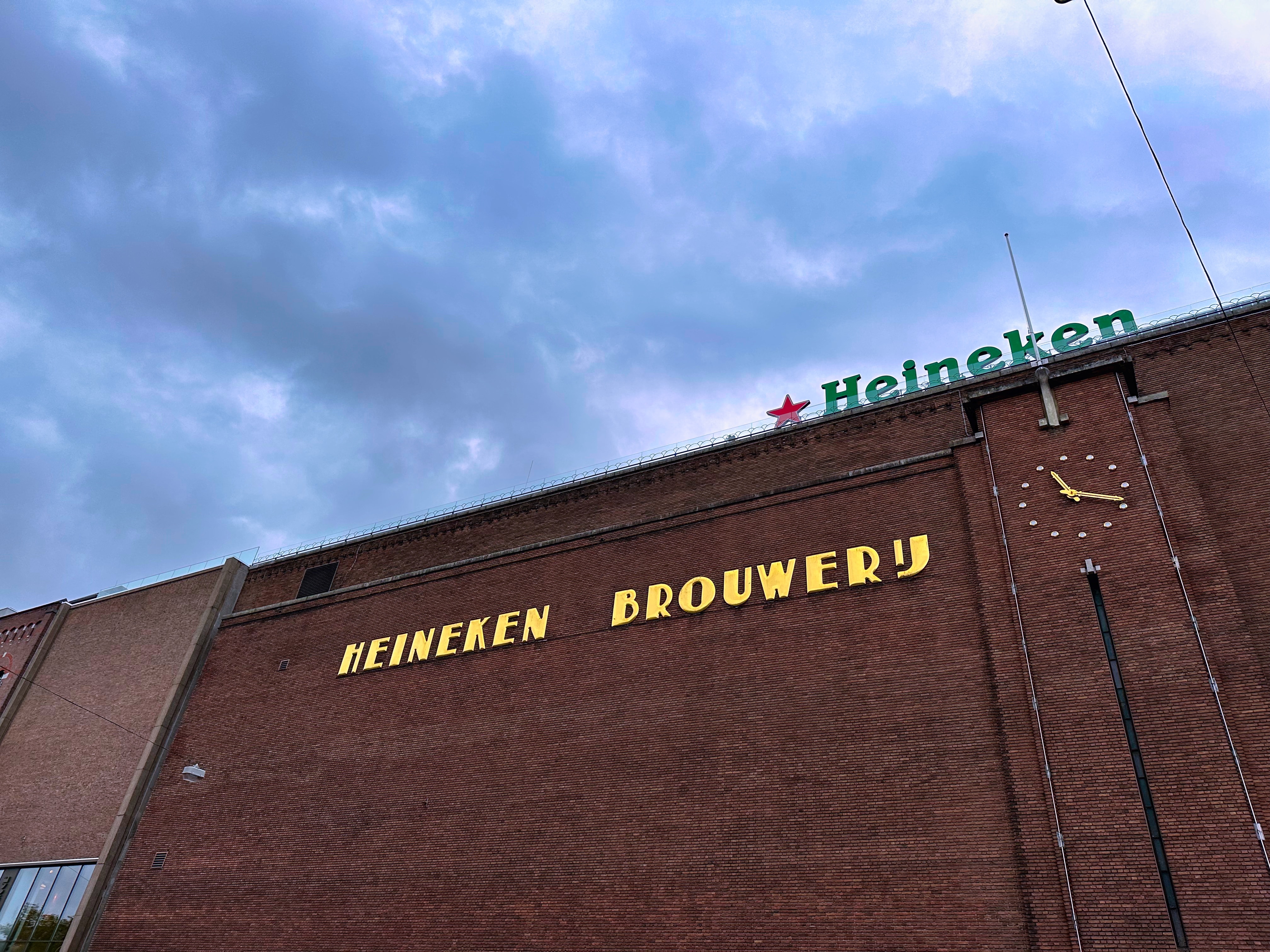 Heineken Experience tour entrance in Amsterdam with visitors entering the historic brewery building.