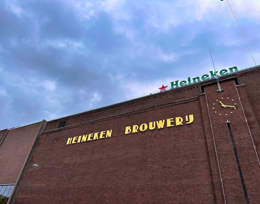 Heineken Experience tour entrance in Amsterdam with visitors entering the historic brewery building.