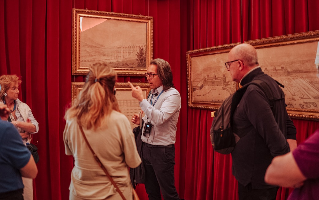 Guide explaining artwork to a small group at Royal Palace of Caserta tour.
