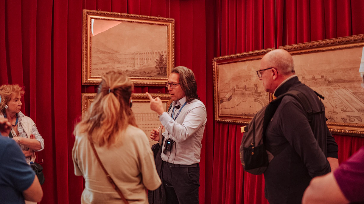 Guide explaining artwork to a small group at Royal Palace of Caserta tour.