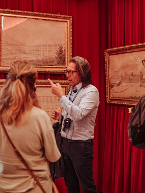 Guide explaining artwork to a small group at Royal Palace of Caserta tour.
