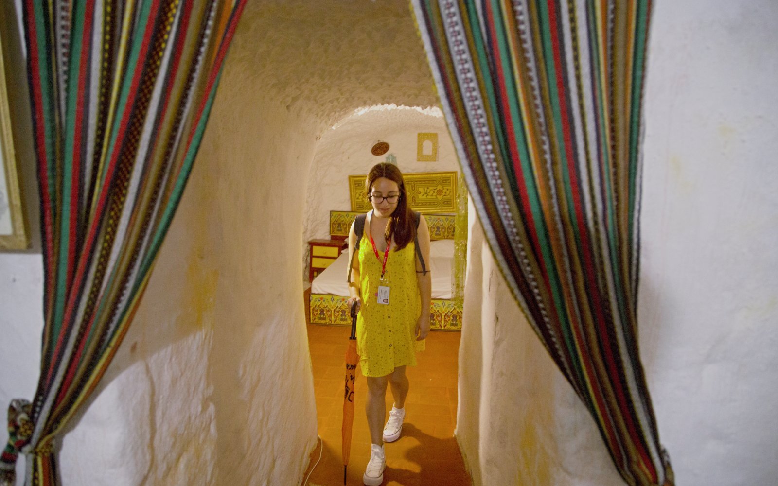 Guide leading through a decorated cave room with colorful curtains.