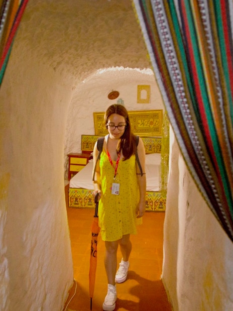 Guide leading through a decorated cave room with colorful curtains.
