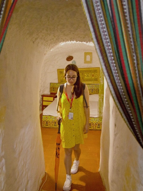 Guide leading through a decorated cave room with colorful curtains.