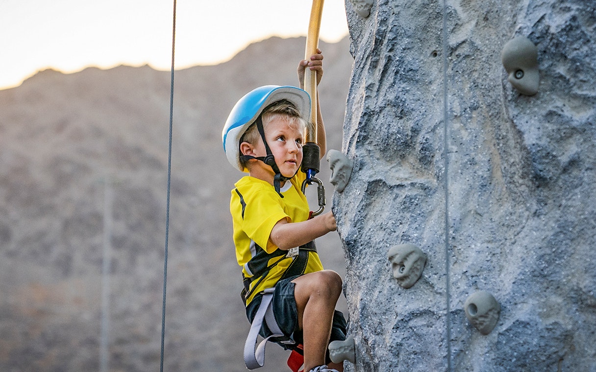 Child climbing rock wall at Fujairah Adventure Park.