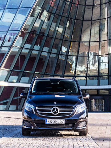 Private transfer vehicle in front of modern glass building at Krakow Airport.